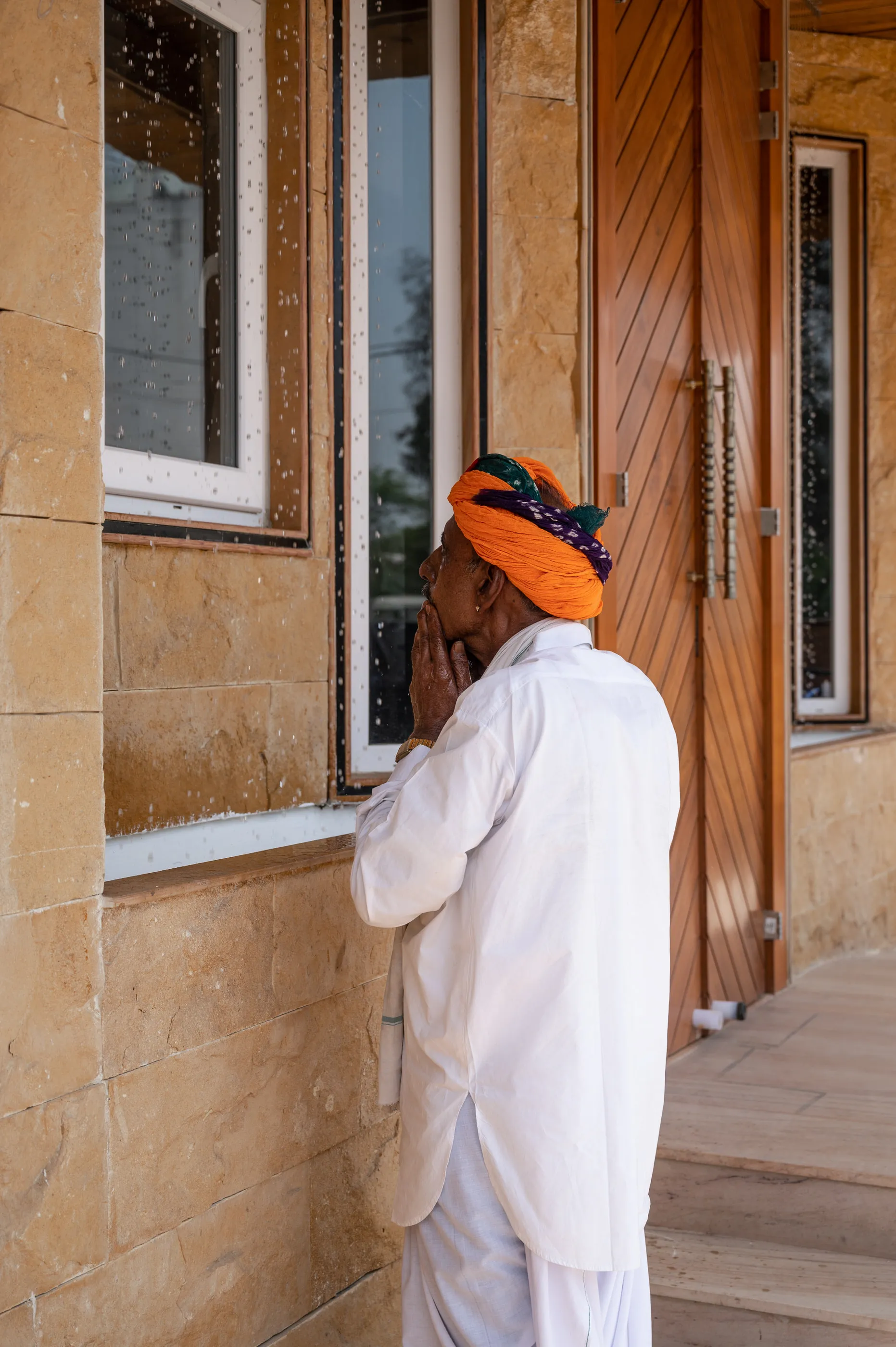 A visitor in an orange turban at a clinic window