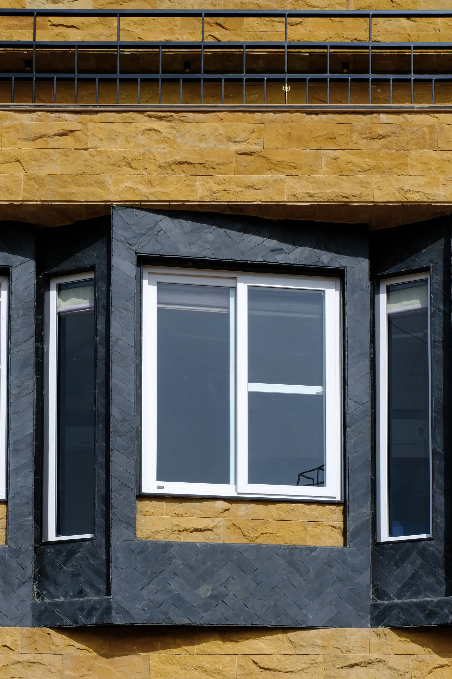 A window set in black granite within the yellow stone facade